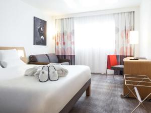 une chambre d'hôtel avec 2 serviettes sur un lit dans l'établissement Novotel Saint-Quentin en Yvelines, à Magny-les-Hameaux