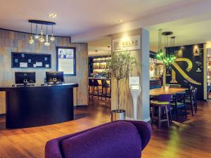 a restaurant with a purple couch and a bar at Mercure München City Center in Munich