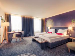 ein Hotelzimmer mit einem großen Bett und einem Schreibtisch in der Unterkunft Mercure München City Center in München