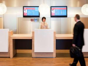 a woman standing behind a counter in a lobby at ibis Aachen Marschiertor - Aix-la-Chapelle in Aachen