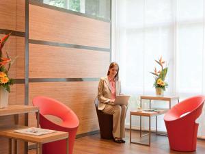 a woman sitting in a chair with a laptop at ibis Aachen Marschiertor - Aix-la-Chapelle in Aachen