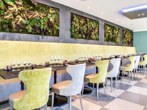 a restaurant with tables and chairs and plants on the wall at Novotel Orléans Saint Jean de Braye in Saint-Jean-de-Braye
