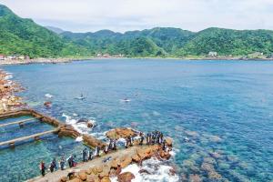 eine Gruppe von Menschen, die auf einem Pier im Wasser stehen in der Unterkunft Ofucos Adventure Hostel in Gongliao