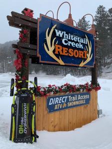 a sign for a wildlife creek resort in the snow at Whitetail Creek Resort in Lead