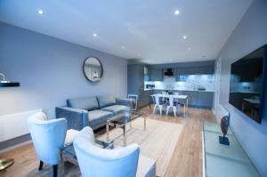 a living room with a couch and chairs and a kitchen at Stunning 2 Bed Merchant City Apartment with Residents Parking (Bell 2) in Glasgow