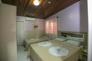 two beds with pillows on them in a bedroom at Pousada Bom Jardim in Chapada dos Guimarães
