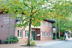 un edificio de ladrillo con un árbol delante de él en Hotel Restaurant "Zur Post" en Holdorf