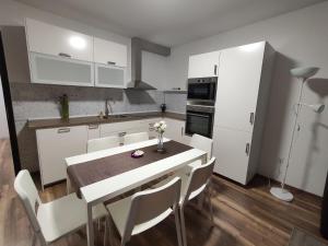une cuisine avec une table et des placards blancs dans l'établissement Hatvan Corner Apartments 2, à Debrecen