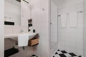 a white bathroom with a sink and a shower at Hotel Esplanade in Gmunden