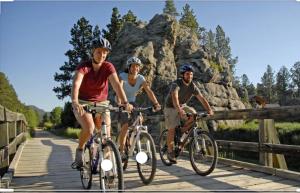 Whitetail Creek Resort في Lead: مجموعة من ثلاثة أشخاص يركبون الدراجات على جسر