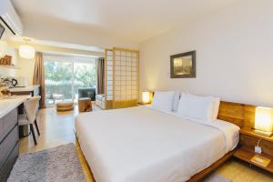 a bedroom with a large white bed and a kitchen at Inn at Moonlight Beach in Encinitas