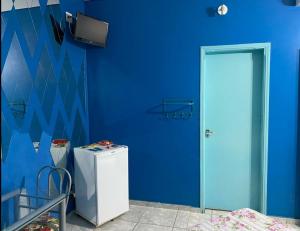 a blue room with a refrigerator and a blue wall at Aquarius Motel IV in Araraquara