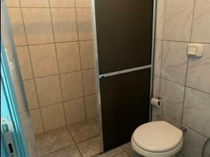 a small bathroom with a toilet and a shower at Aquarius Motel IV in Araraquara