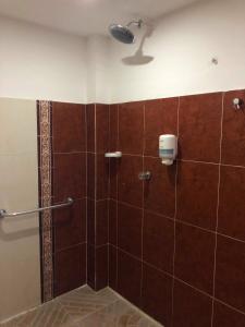 bagno con doccia e piastrelle marroni di Hotel Yurupary AMAZONAS a Leticia