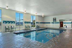 una piscina con sillas, mesas y ventanas en Oxford Suites Yakima, en Yakima