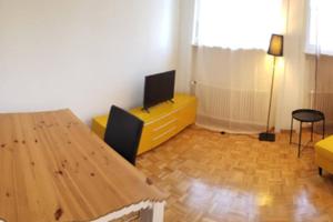 a living room with a wooden table and a television at HSH Barre 6 - City Apartment next Cathedral Lausanne in Lausanne