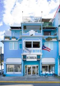a blue and white building with a flag on it at Nomada Urban Beach Hostel- Calle Loiza in San Juan