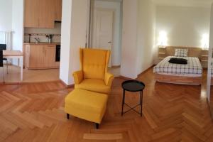 a living room with a yellow chair and a bed at HSH Boston - Moderne Junior Suite-Apartment 36 m2 - Lausanne in Lausanne