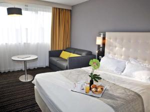 una camera d'albergo con letto e divano di Mercure Bourg En Bresse a Bourg-en-Bresse