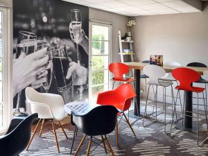 a bar with red chairs and a wall with a picture of wine glasses at ibis Sisteron in Sisteron