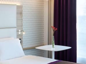 una habitación con una cama y una mesa con un jarrón. en Mercure Paris Orly Rungis Aéroport en Rungis