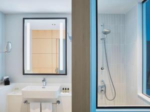 a bathroom with a shower, sink, and toilet at Hotel Mondial am Dom Cologne MGallery in Cologne