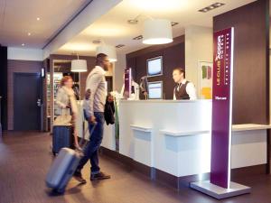 a group of people walking in a lobby with luggage at Mercure Hotel Den Haag Central in The Hague