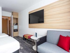 アヌシーにあるNovotel Annecy Centreのベッド、ソファ、テレビが備わるホテルルームです。