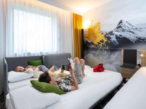 two children laying on a bed in a room at Novotel Annecy Centre in Annecy