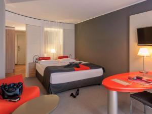 フランクフルト・アム・マインにあるメルキュール レジデンツ フランクフルト メッセの大きなベッドとテーブルが備わるホテルルームです。