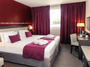 um quarto de hotel com duas camas e uma secretária em Mercure Bayeux Omaha Beach em Port-en-Bessin-Huppain