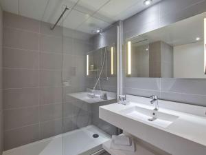 a bathroom with a sink and a mirror and a tub at Mercure Paris Roissy CDG in Roissy-en-France