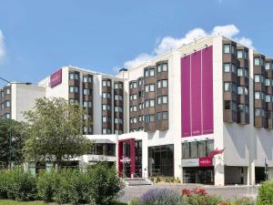 a large white building with red and purple windows at Mercure Reims Centre Cathédrale in Reims