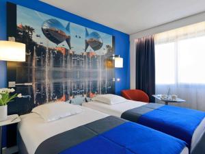 a hotel room with two beds and a mural at Mercure Nice Centre Notre Dame in Nice