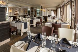 uma sala de jantar com mesas e cadeiras brancas e uma mesa de trabalho em Cobo Bay Hotel em Castel