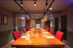 a long wooden table in a room with red chairs at The Farmhouse Hotel and Restaurant in St Saviour Guernsey