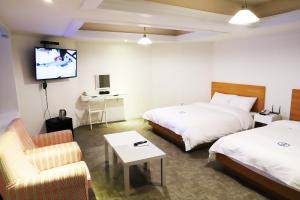 a hotel room with two beds and a flat screen tv at Hillside Hotel in Busan