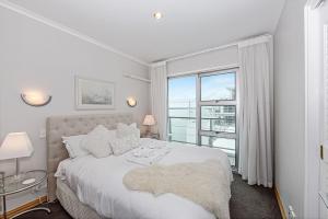a white bedroom with a large bed and a window at Princes Wharf 2BR Sub-Penthouse in Auckland