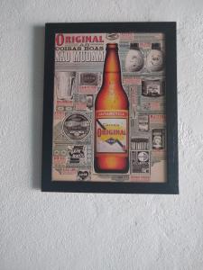 una imagen enmarcada de una botella de alcohol en una pared en Chalés Marazul Toninhas, en Ubatuba