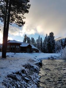 a house in the snow next to a creek at The Wild Game Inn in Alta