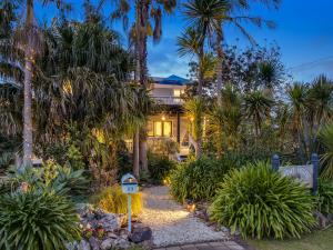 a house with palm trees and a sign in front of it at Kiwi House Waiheke in Oneroa