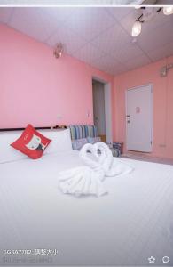 a towel on a bed in a room with pink walls at Happy Homestay in Budai