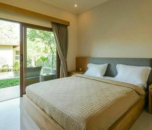 a bedroom with a large bed and a large window at Arnaya Homestay in Kuta