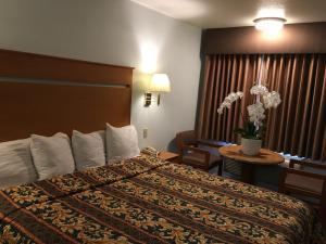 ハンティントンビーチにあるオーシャン ビュー モーテルのベッド、椅子、テーブルが備わるホテルルームです。