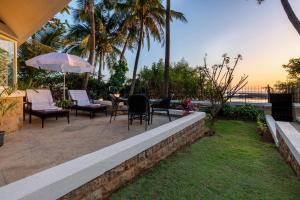 a patio with chairs and a table with an umbrella at amã Stays & Trails, Beach House Madh Island in Mumbai