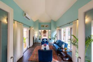 een woonkamer met een blauwe bank en ramen bij amã Stays & Trails, Beach House Madh Island in Mumbai