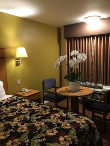 um quarto de hotel com uma cama e uma mesa com flores em OceanView Motel em Huntington Beach