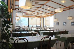 a dining room with tables and chairs and large windows at Nakanoyu Onsen Ryokan in Matsumoto