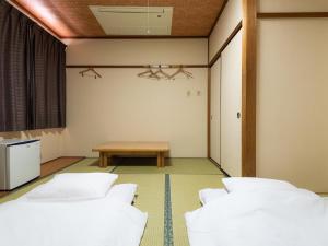 a room with three white beds and a table at Tabist Hotel Kurama Hikone in Takamiya