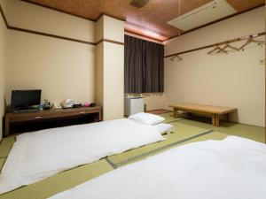 a bedroom with two beds and a tv and a table at Tabist Hotel Kurama Hikone in Takamiya